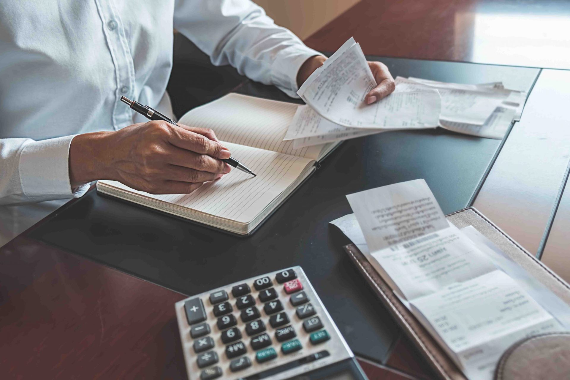 Woman with bills and calculator. Woman using calculator to calculate bills at the table in office. Calculation of costs.